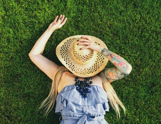 Unknown Tattooed Woman Relaxing on Grass in Hat and Dress at Summer